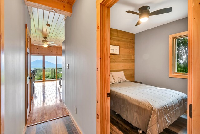 bedroom featuring ceiling fan, a mountain view, hardwood / wood-style flooring, and multiple windows