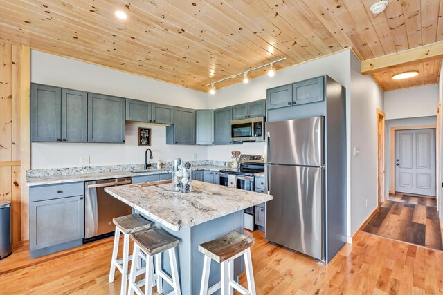 kitchen with light hardwood / wood-style flooring, track lighting, wooden ceiling, a center island, and stainless steel appliances