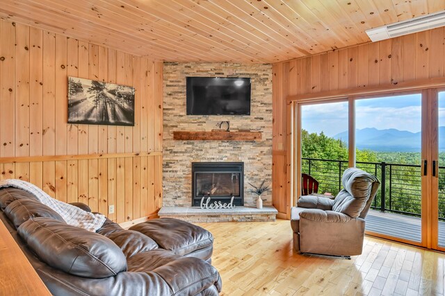 living room featuring light hardwood / wood-style floors, wood ceiling, wooden walls, and a fireplace