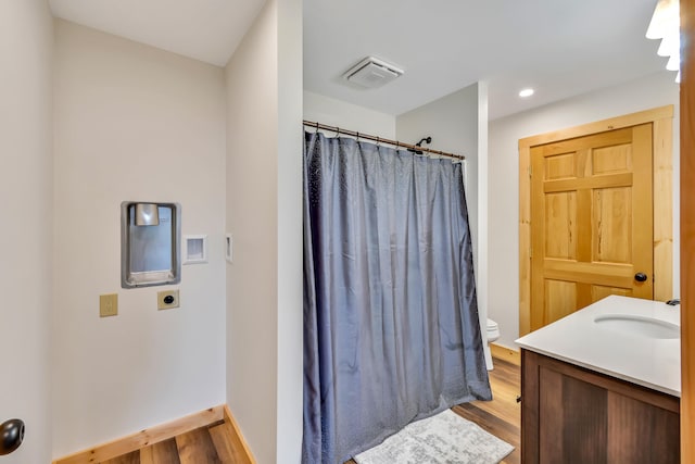 bathroom featuring toilet, hardwood / wood-style floors, and vanity