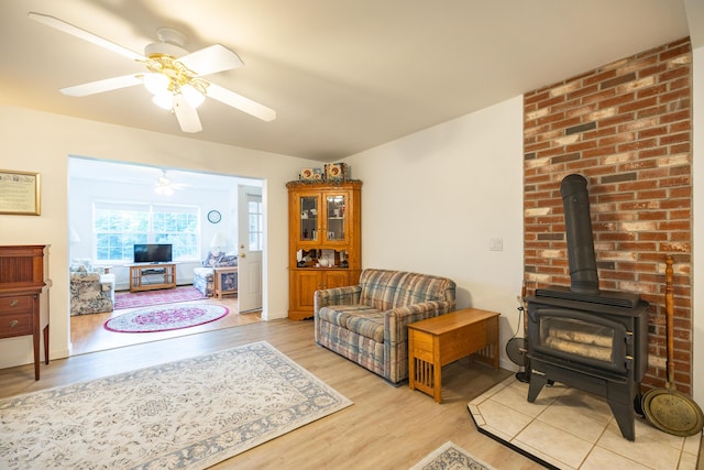 living room with light hardwood / wood-style flooring, a wood stove, and ceiling fan