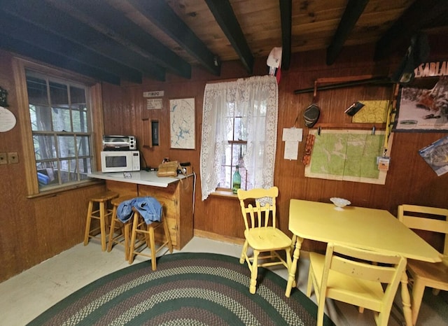 kitchen featuring a breakfast bar, beam ceiling, and wooden walls