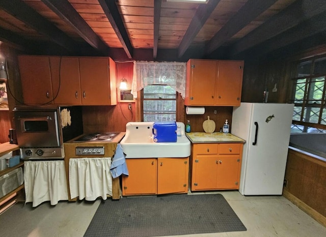 kitchen featuring beam ceiling, wooden walls, plenty of natural light, and white refrigerator