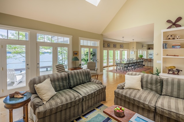 living room featuring light hardwood / wood-style floors, high vaulted ceiling, and french doors