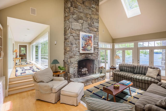 living room with french doors, high vaulted ceiling, a healthy amount of sunlight, and light wood-type flooring