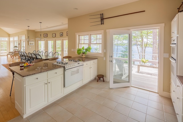 kitchen with white gas range oven, white cabinetry, and a healthy amount of sunlight