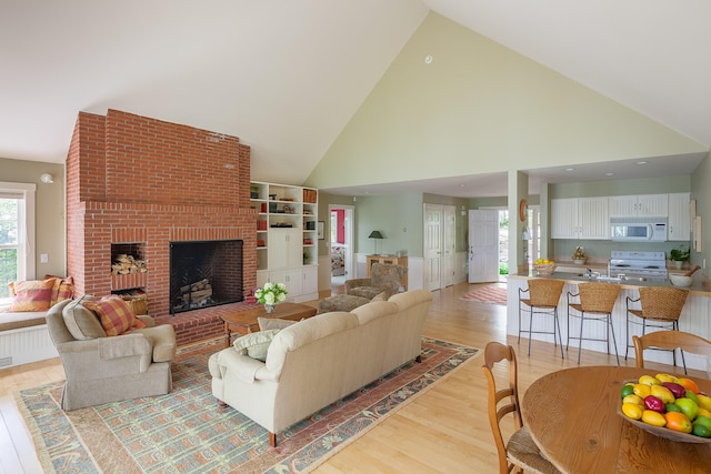 living room featuring a fireplace, high vaulted ceiling, and light hardwood / wood-style floors