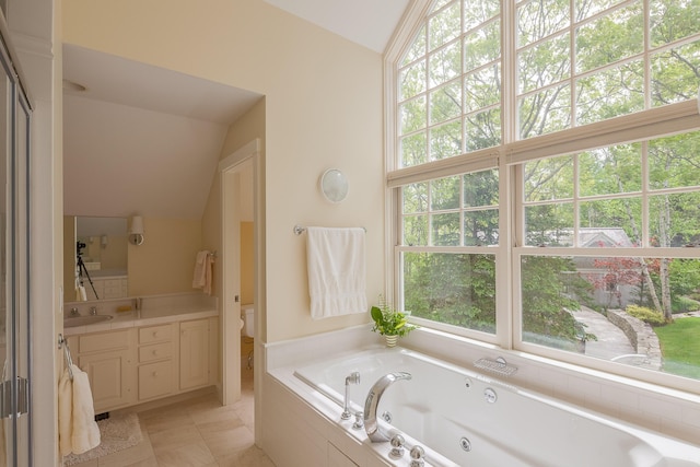 bathroom with tile patterned floors, vaulted ceiling, plenty of natural light, and tiled tub