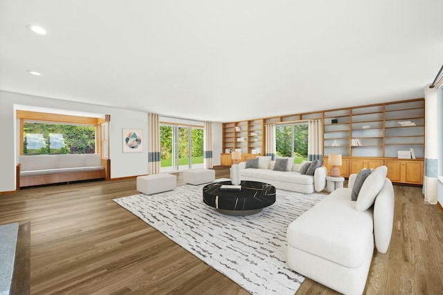 living area featuring built in shelves, recessed lighting, and light wood-type flooring