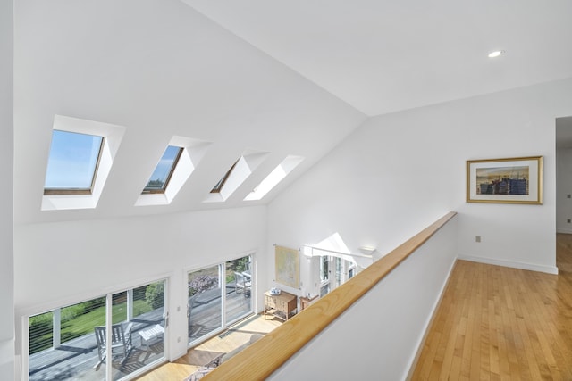 hall with light wood-type flooring and high vaulted ceiling