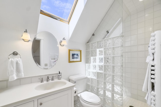 bathroom featuring a tile shower, lofted ceiling with skylight, vanity, and toilet