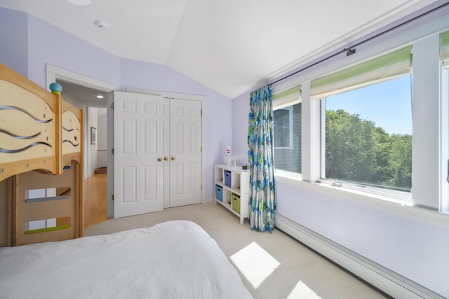 bedroom with vaulted ceiling, light carpet, a baseboard heating unit, and a closet