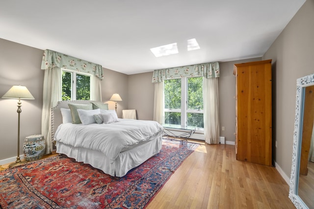 bedroom featuring light wood-type flooring, a skylight, and multiple windows