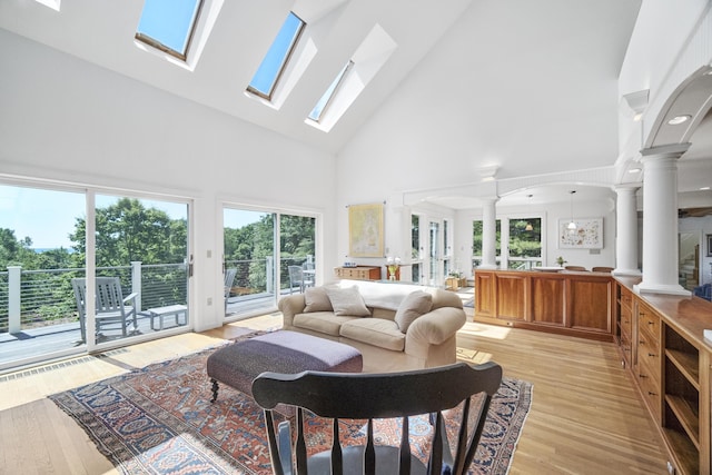 living room featuring light wood-type flooring, high vaulted ceiling, and ornate columns