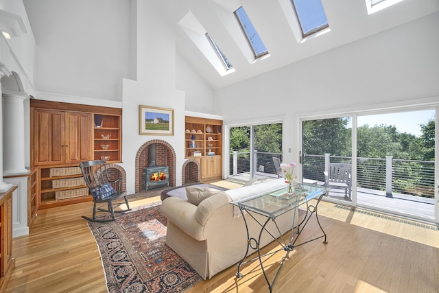 living room with high vaulted ceiling, a wood stove, and light hardwood / wood-style floors