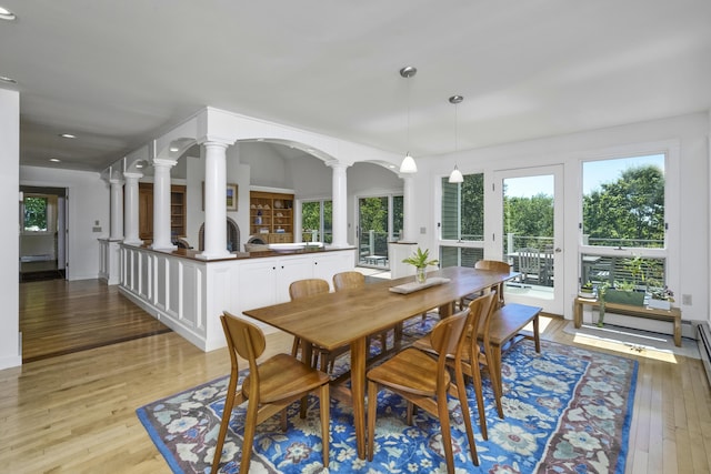 dining area with light hardwood / wood-style floors and ornate columns