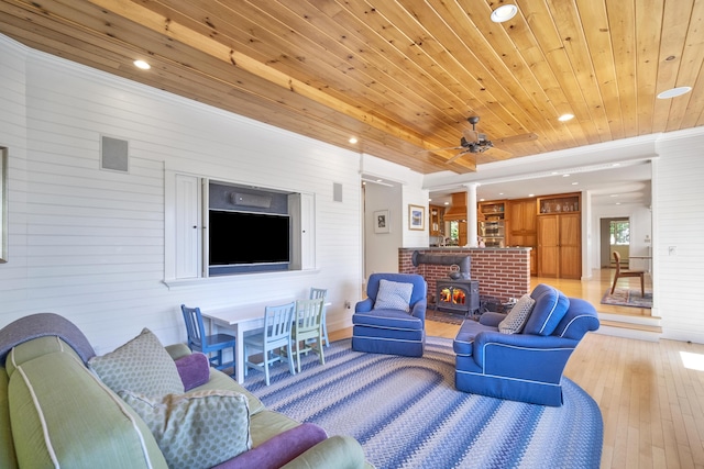 living room with wood ceiling, a wood stove, ceiling fan, and wood-type flooring