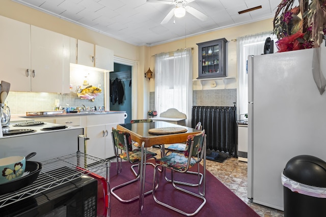 kitchen featuring radiator, white cabinetry, white refrigerator, ceiling fan, and crown molding