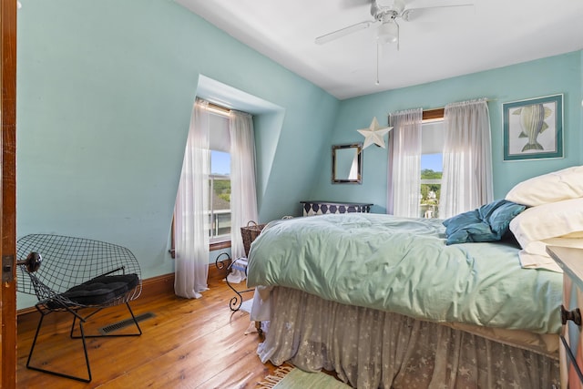 bedroom with ceiling fan, wood-type flooring, and multiple windows