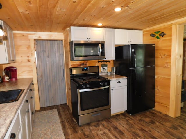 kitchen with appliances with stainless steel finishes, dark wood-type flooring, white cabinetry, sink, and wood walls