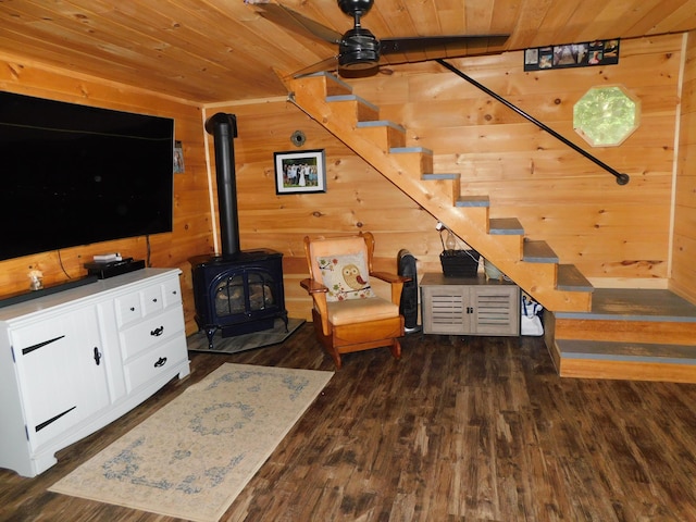 living room with dark hardwood / wood-style flooring, wood ceiling, wooden walls, and a wood stove