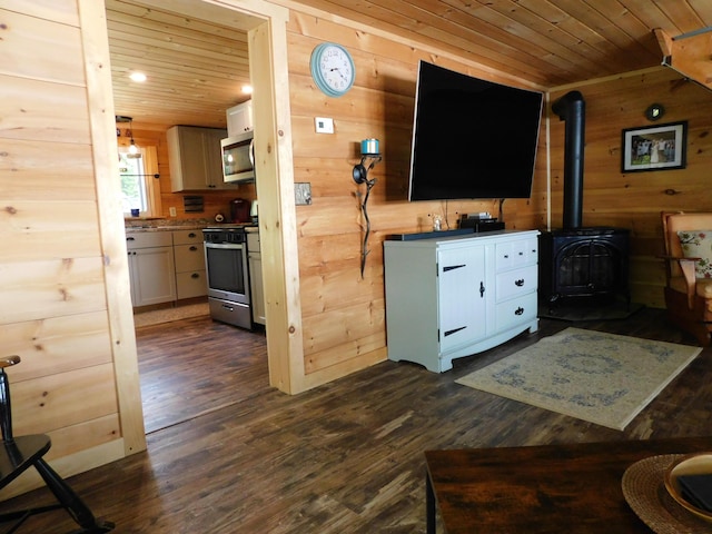 living room with dark hardwood / wood-style floors, wooden walls, a wood stove, and wooden ceiling