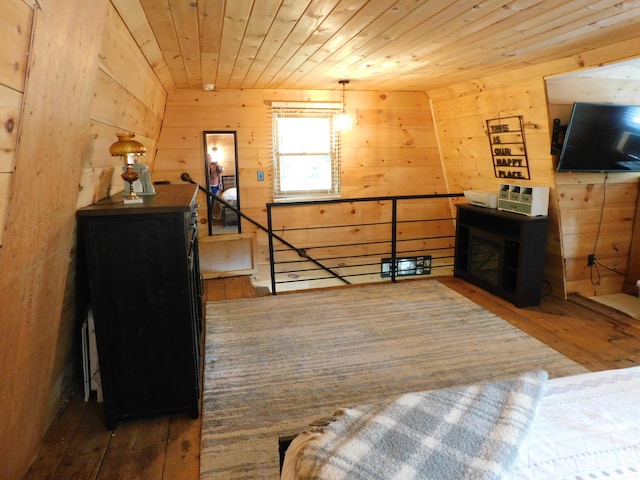 bedroom with wooden ceiling, dark hardwood / wood-style floors, and wood walls