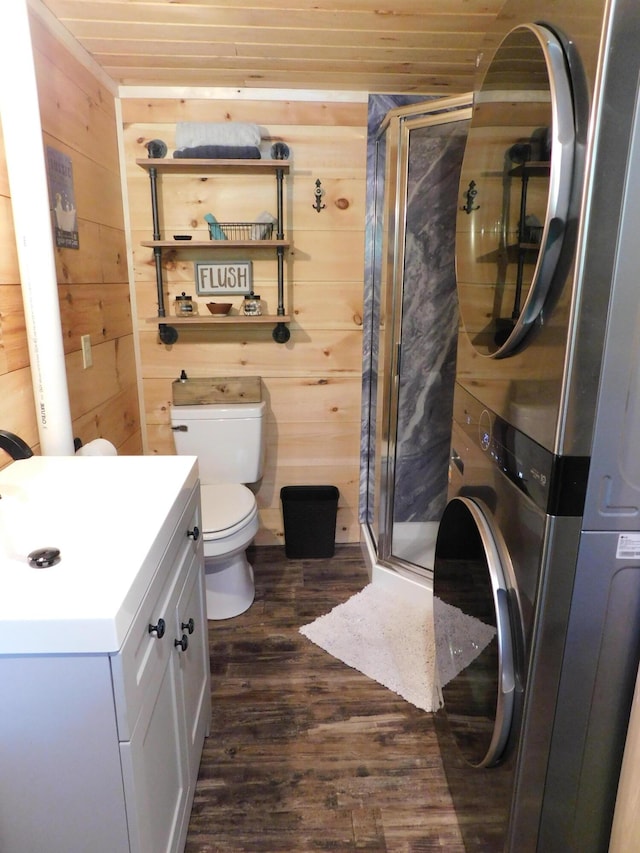 bathroom featuring vanity, wooden walls, hardwood / wood-style flooring, stacked washer and dryer, and wooden ceiling