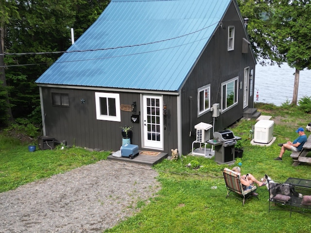 rear view of house featuring an outbuilding, a water view, and a yard