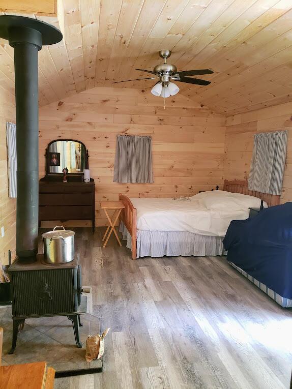 unfurnished bedroom featuring hardwood / wood-style floors, wooden walls, wooden ceiling, ceiling fan, and vaulted ceiling