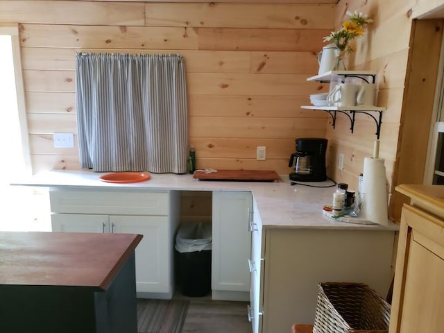 kitchen featuring white cabinetry and wooden walls