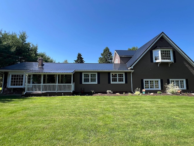 view of front of property with metal roof, a porch, a chimney, and a front yard