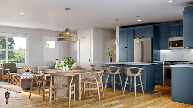 kitchen with pendant lighting, blue cabinetry, backsplash, stainless steel appliances, and light hardwood / wood-style floors