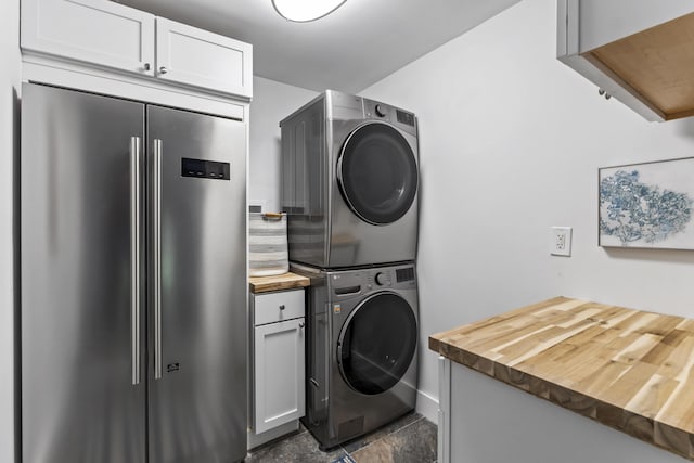 laundry area featuring cabinets and stacked washer and clothes dryer