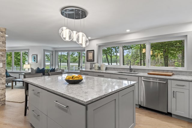 kitchen featuring sink, light stone counters, a center island, hanging light fixtures, and dishwasher