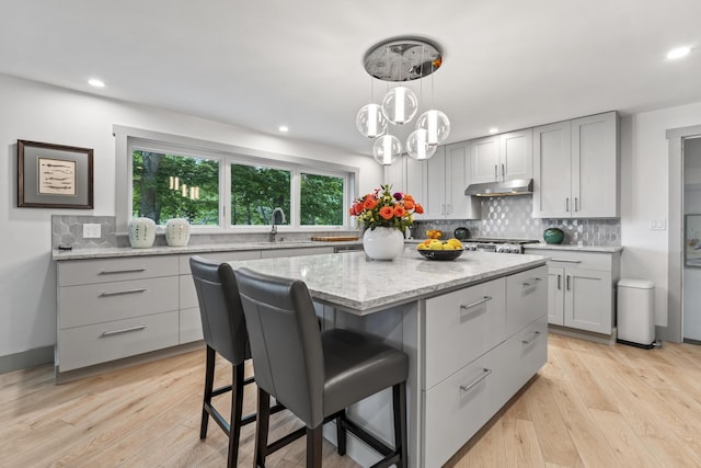 kitchen featuring sink, gray cabinets, a kitchen island, light hardwood / wood-style floors, and decorative backsplash