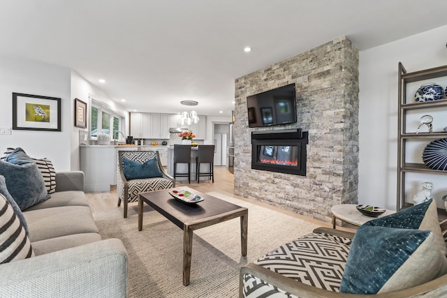 living room with a stone fireplace, sink, and light wood-type flooring