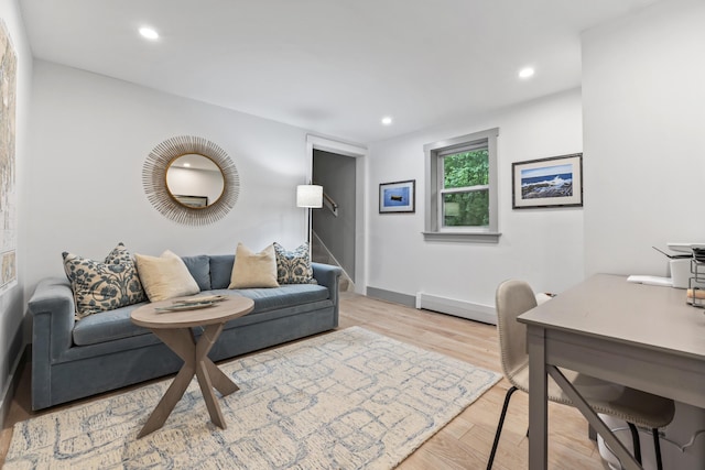 living room with a baseboard heating unit and light hardwood / wood-style floors