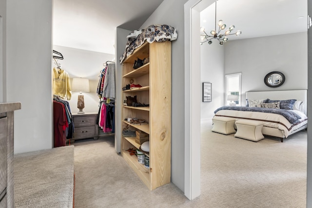 walk in closet featuring light colored carpet and an inviting chandelier