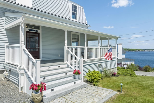 doorway to property with a lawn, a water view, and a porch