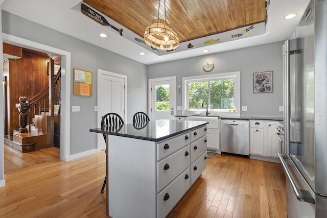 kitchen with stainless steel appliances, a tray ceiling, a center island, and white cabinets