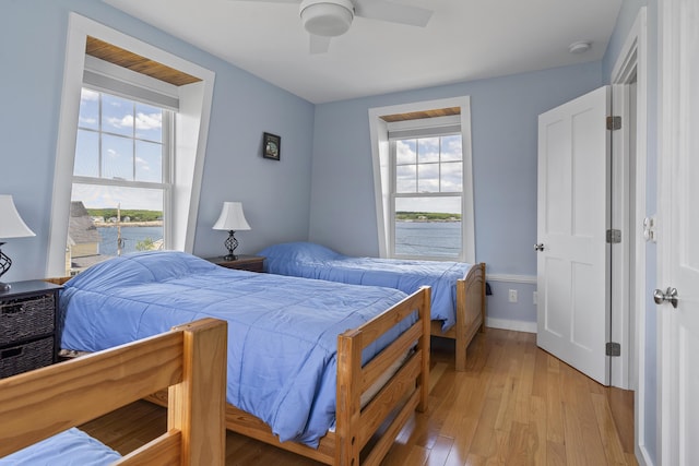 bedroom with ceiling fan, multiple windows, and light hardwood / wood-style flooring