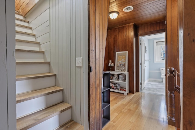 hall featuring wooden ceiling, wooden walls, and light hardwood / wood-style floors