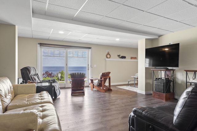 living room with a drop ceiling and dark wood-type flooring