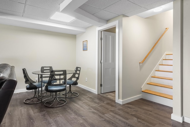 dining space with dark hardwood / wood-style floors and a drop ceiling