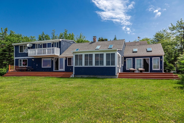 rear view of house featuring a deck, a balcony, and a lawn