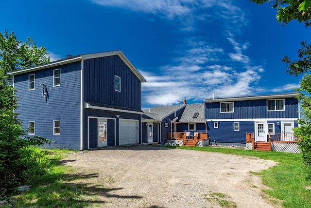 rear view of property with a wooden deck and a garage