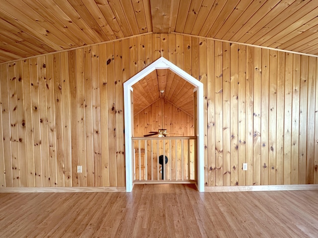 additional living space featuring lofted ceiling, wood ceiling, wooden walls, ceiling fan, and hardwood / wood-style flooring