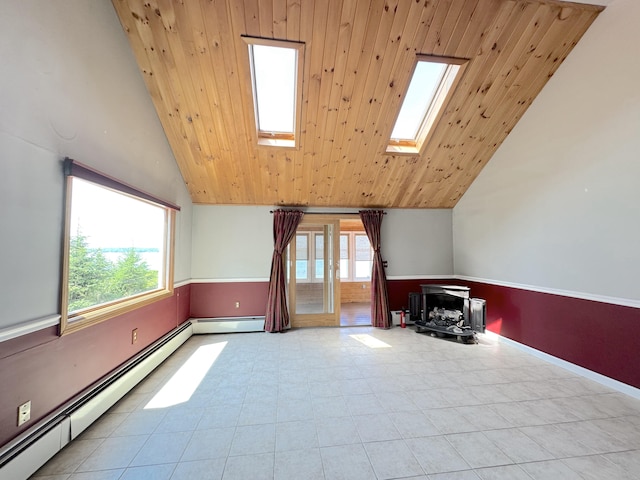 additional living space featuring a wood stove, a baseboard heating unit, vaulted ceiling with skylight, and wood ceiling