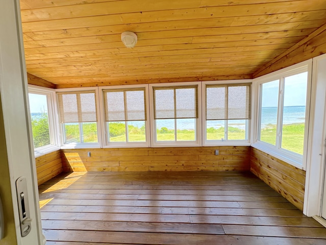 unfurnished sunroom featuring wood ceiling, a wealth of natural light, lofted ceiling, and a water view